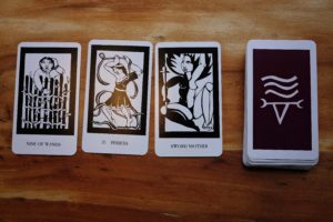3 tarot cards face-up and the rest of the deck in a pile on a wooden background