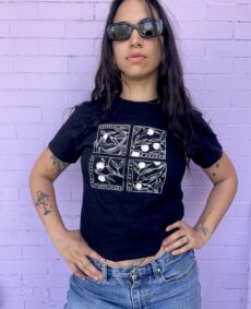 Photograph of model Kristeen Lynch wearing a black Metonymy t-shirt designed by Lee Lai against a purple brick background.