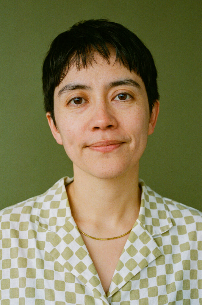 Felix Chau Bradley headshot, wearing a green checkered shirt, with a green background