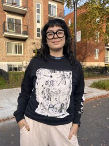 A photo of shirt model Marcela Huerta wearing a Metatron x Metonymy Shirt designed by Janes Harmes. Marcela is wearing a Black shirt with a design printed in white ink.