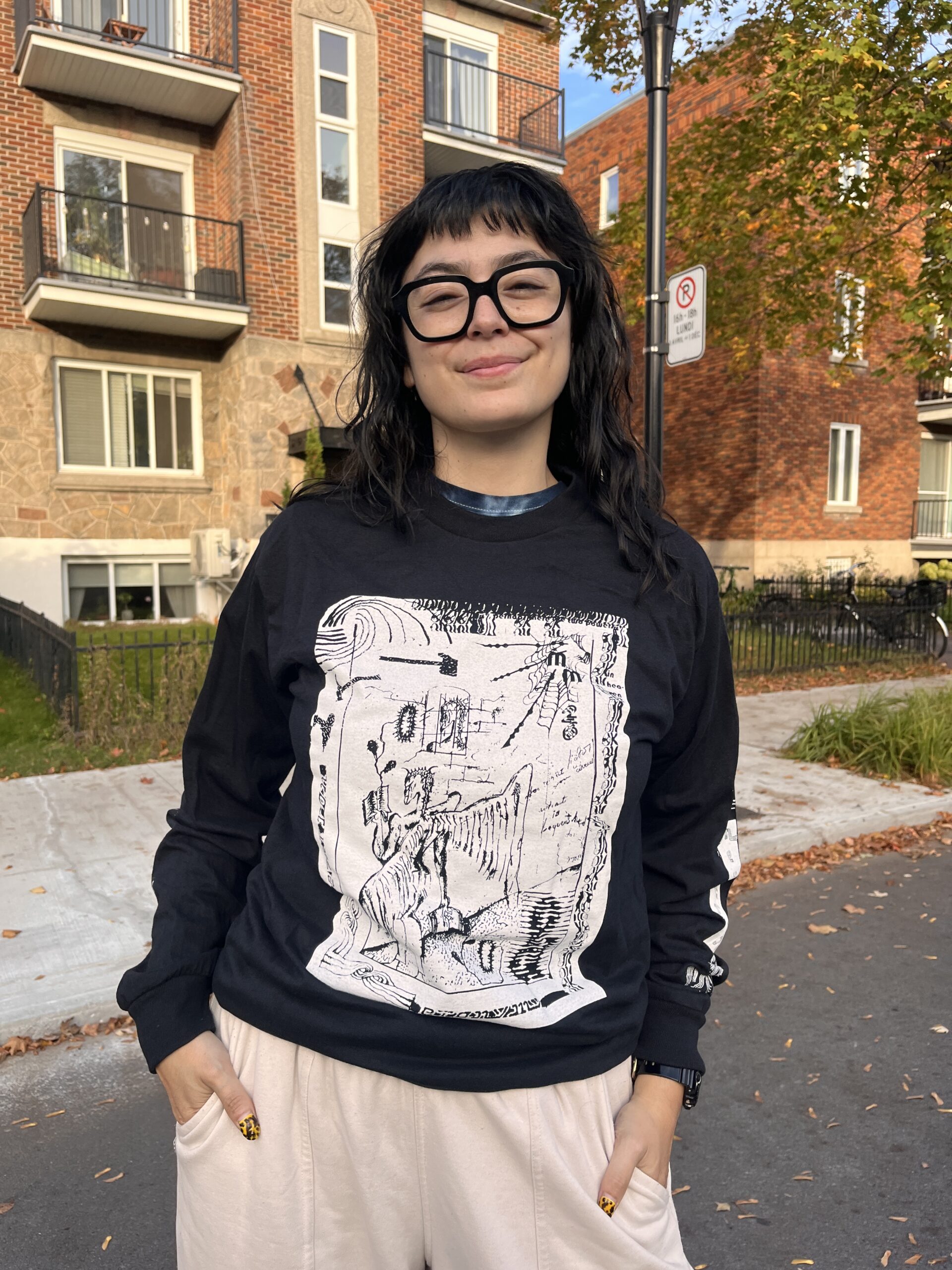 A photo of shirt model Marcela Huerta wearing a Metatron x Metonymy Shirt designed by Janes Harmes. Marcela is wearing a Black shirt with a design printed in white ink.